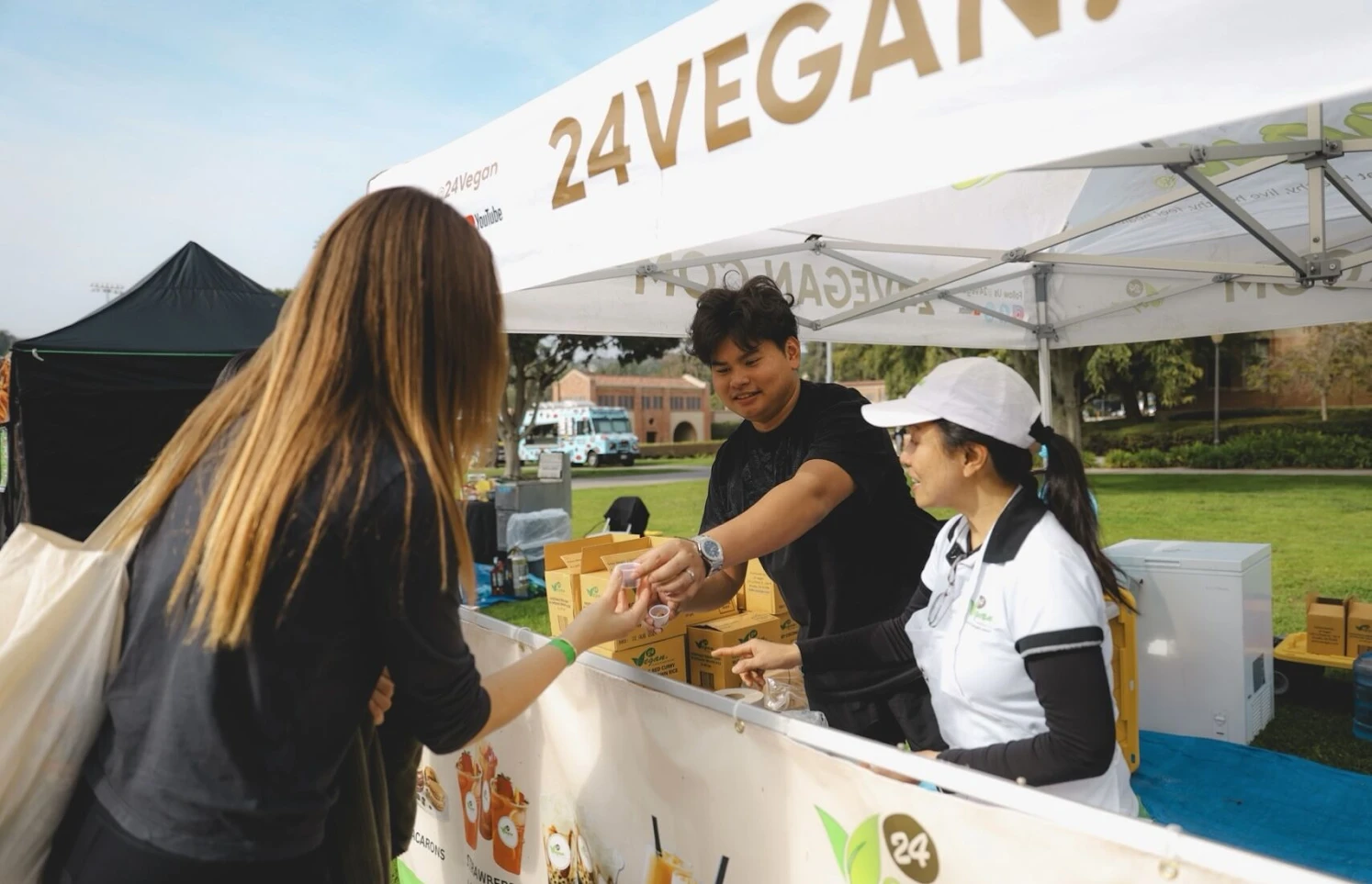 A visitor receiving a food sample at a 24Vegan booth